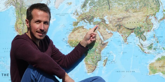 Fernreisen mit Kindern - For Family Reisen auf Tournee mit Willi Weitzel - Mann zeigt auf Weltkarte