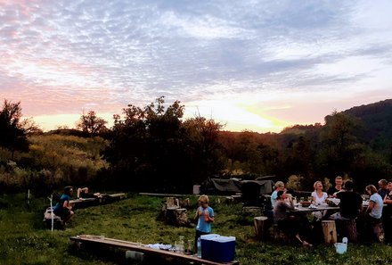 Familienreise Rumänien - Alma Vii - Gruppe sitzt zusammen beim Sonnenuntergang