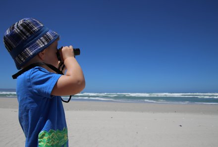 Familienreise Garden Route - Südafrika Family & Teens - Hermanus - Kind mit Fernglas am Strand