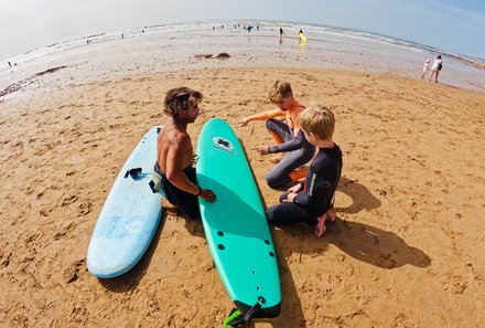 Marokko Family & Teens - Marokko mit Jugendlichen - jugendliche sitzen mit Surfbrettern am Strand
