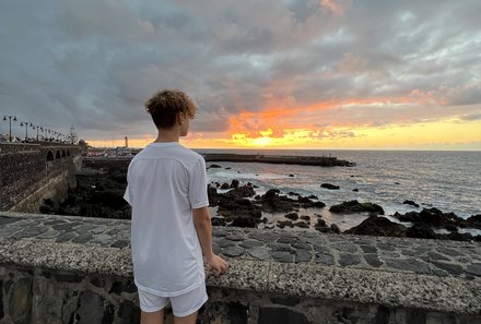 Teneriffa Familienurlaub - Teneriffa for family - Puerto de la Cruz - Junge schaut aufs Meer bei Sonnenuntergang - Wellen 